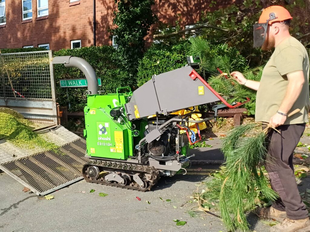 Photo of an Ohashi ES151GH 6-inch compact tracked woodchipper on a street chipping foliage into a trailer