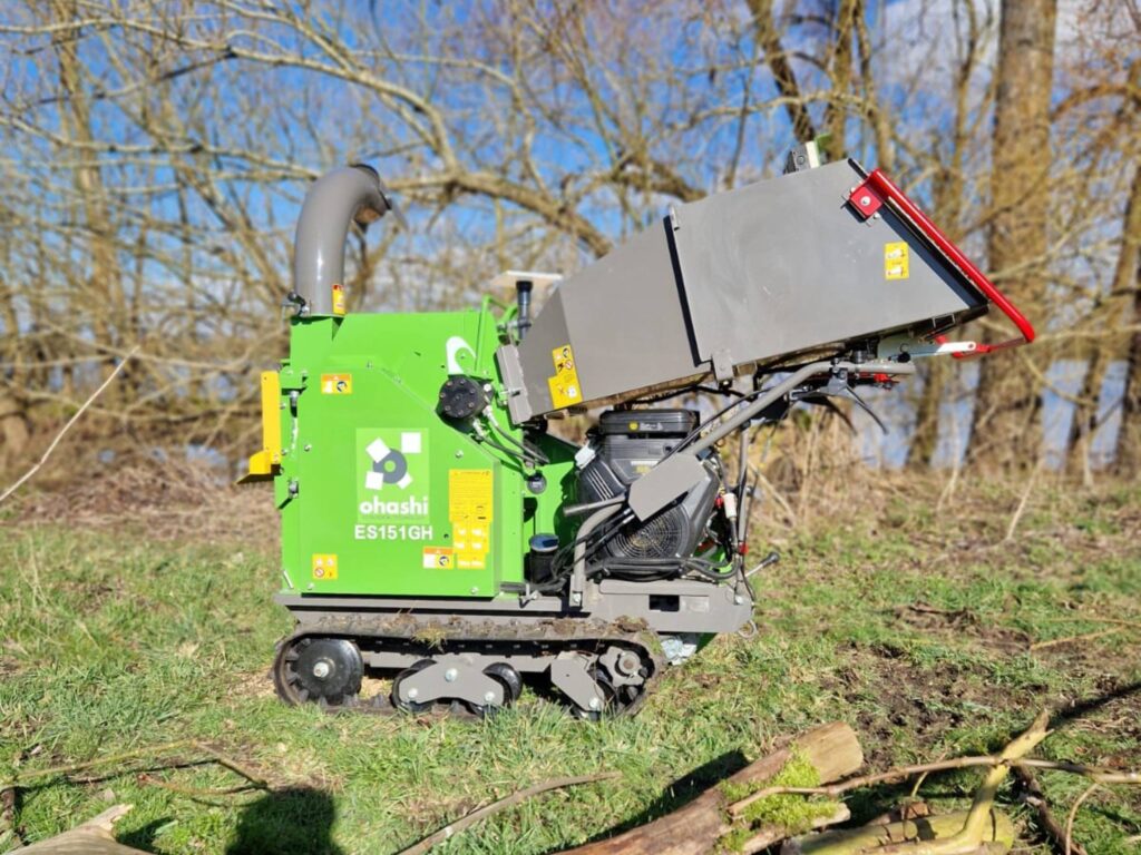 Photo of an Ohashi ES151GH 6-inch compact tracked woodchipper outside on some grass chipping wood by a tree